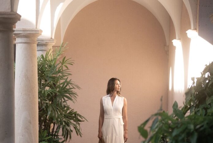 Woman in courtyard with arched architecture.