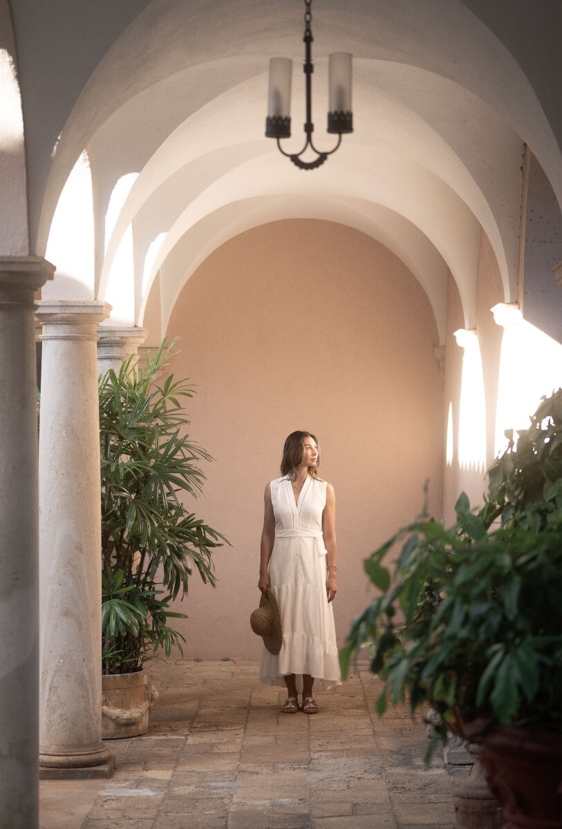 Woman in courtyard with arched architecture.